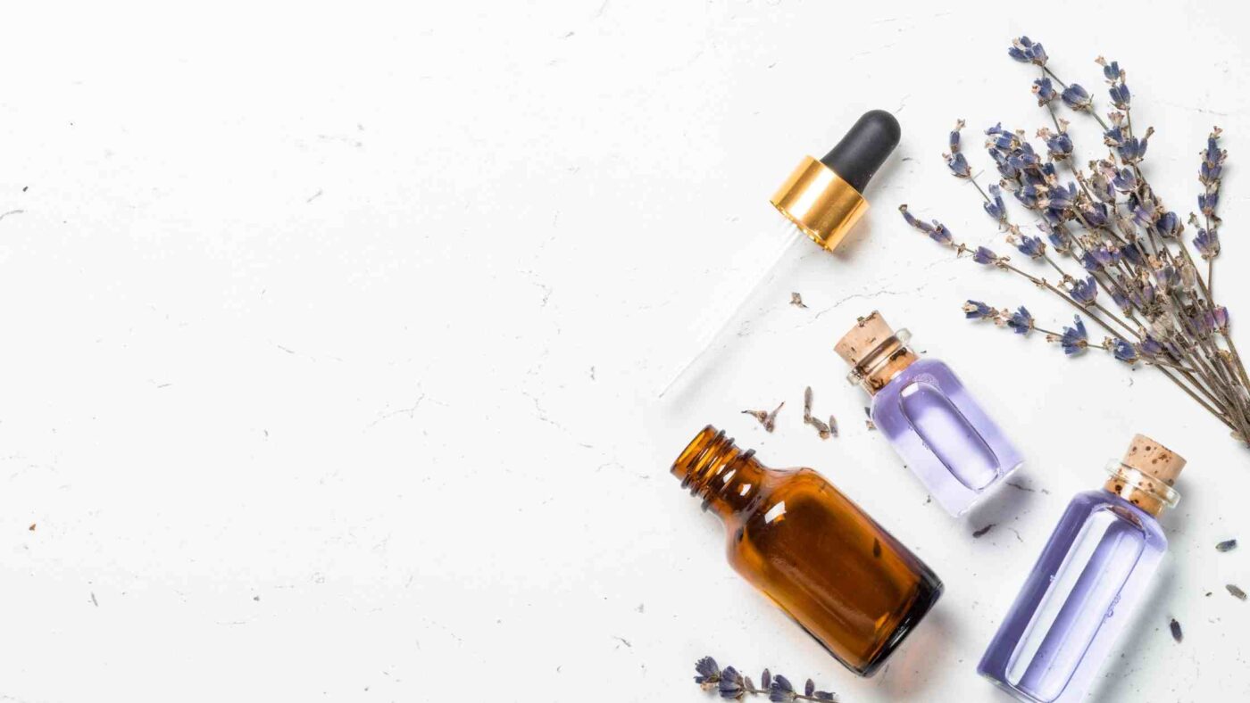 The image shows bottles of essential oils, a dropper, and dried lavender sprigs arranged on a white surface, suggesting the concept of diffusing colloidal silver and essential oils together