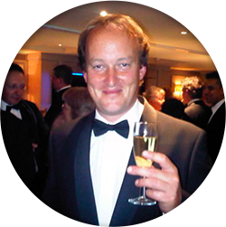 A man in a tuxedo holding a glass of champagne.