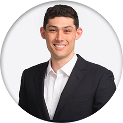 A man in a suit is smiling in front of a white background.