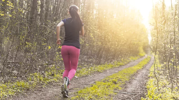 young woman running through a forest