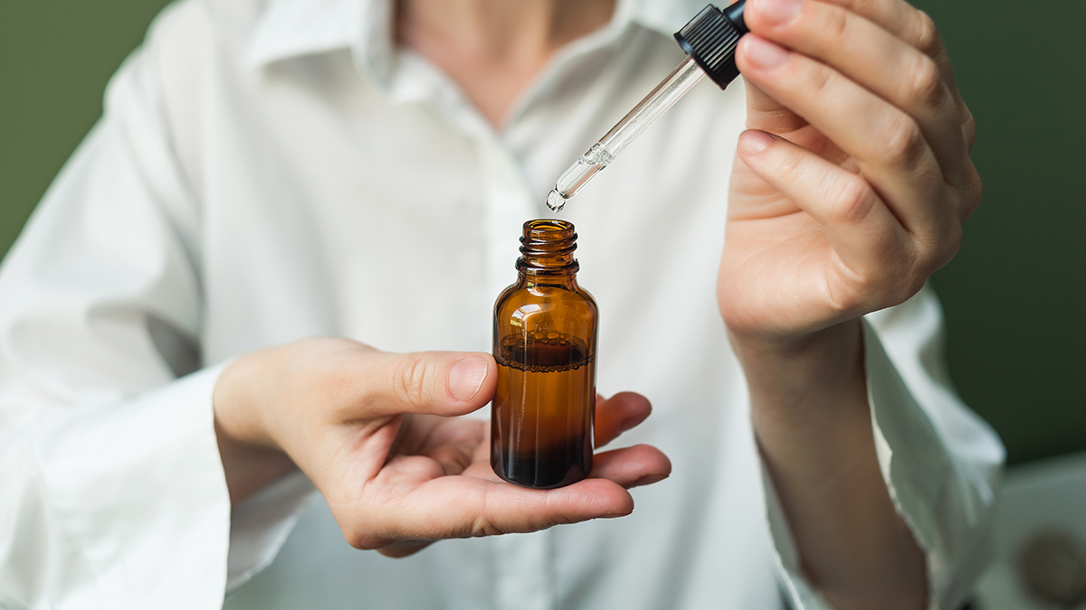 A person using a dropper with an amber bottle; choose pet-safe