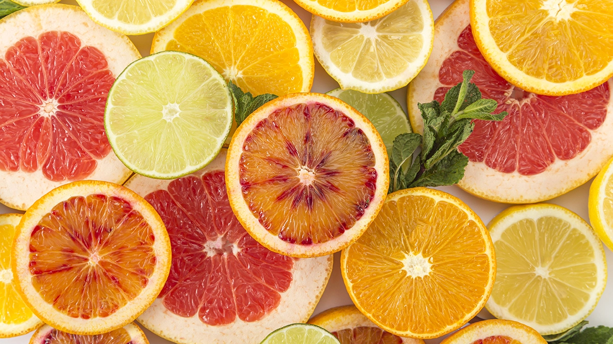 Slices of various citrus fruits including oranges, grapefruits, lemons, and limes, with fresh mint leaves