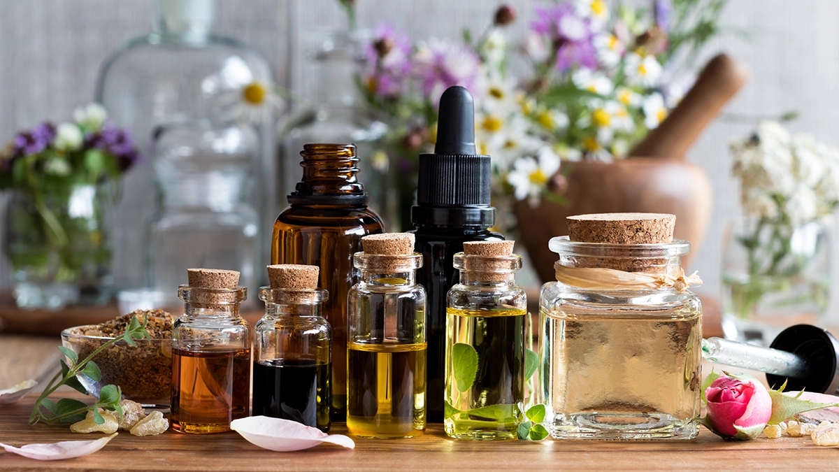 A collection of essential oil bottles surrounded by flowers and herbs, representing natural remedies for adrenal fatigue