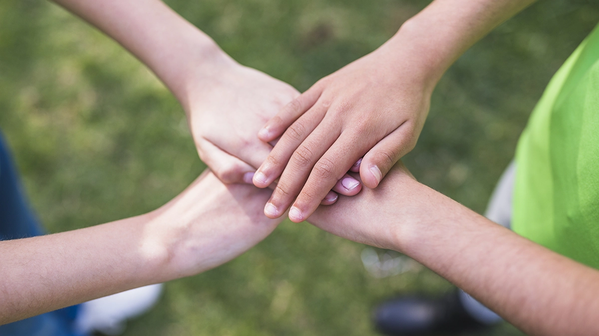 Three friends stacking their hands together symbolizing unity and support Understanding Hand Foot Mouth Disease