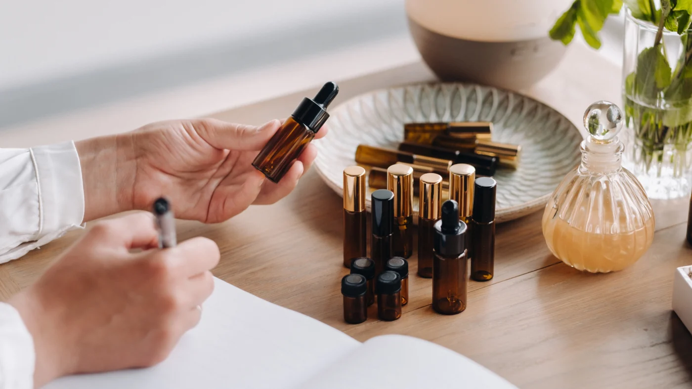  A person holding an amber dropper bottle with various essential oils and suggesting natural remedies for hemorrhoids