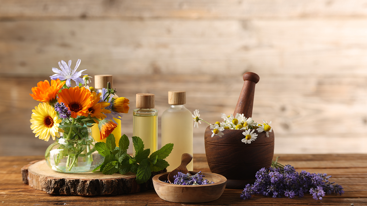 Essential oils, herbs, and flowers for natural cleaning on a rustic table