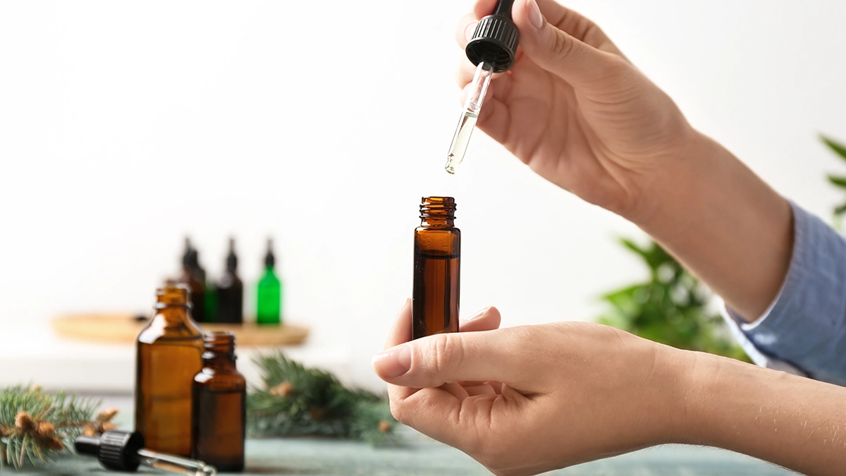 Hands using a dropper with essential oil, which may help manage lupus symptoms like inflammation and stress