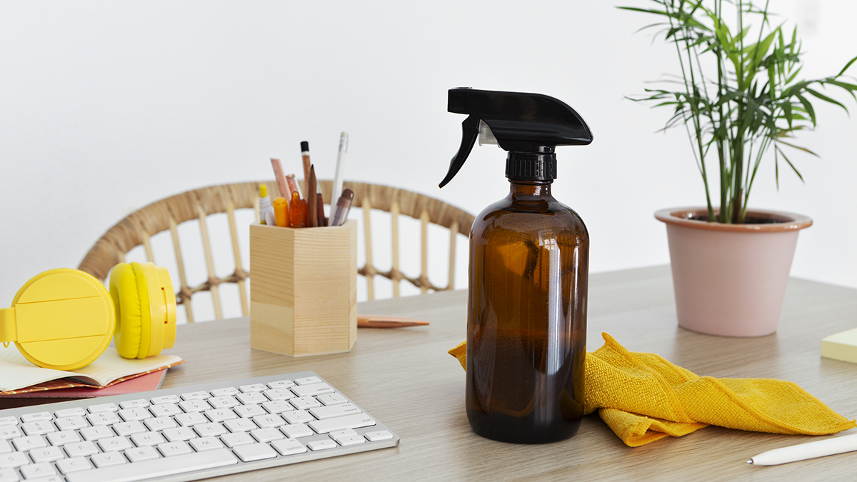 spray bottle with cloth on a desk, promoting natural cleaning with essential oils