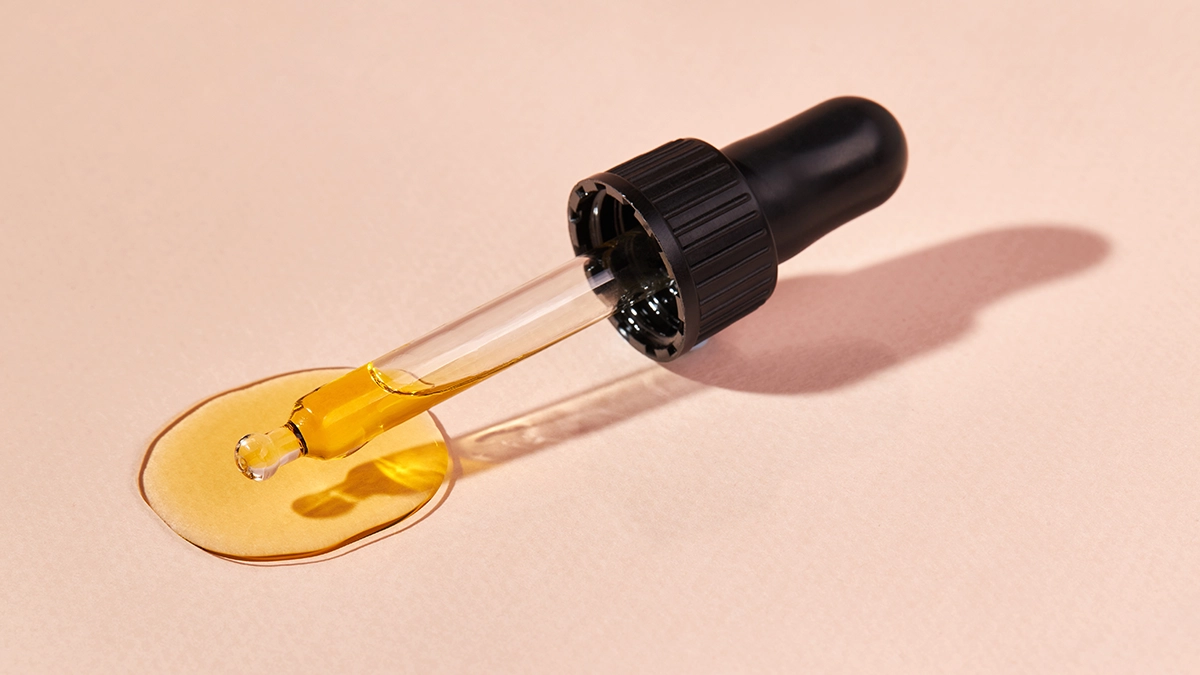 A dropper with golden essential oil, representing safe use for stomach pain relief