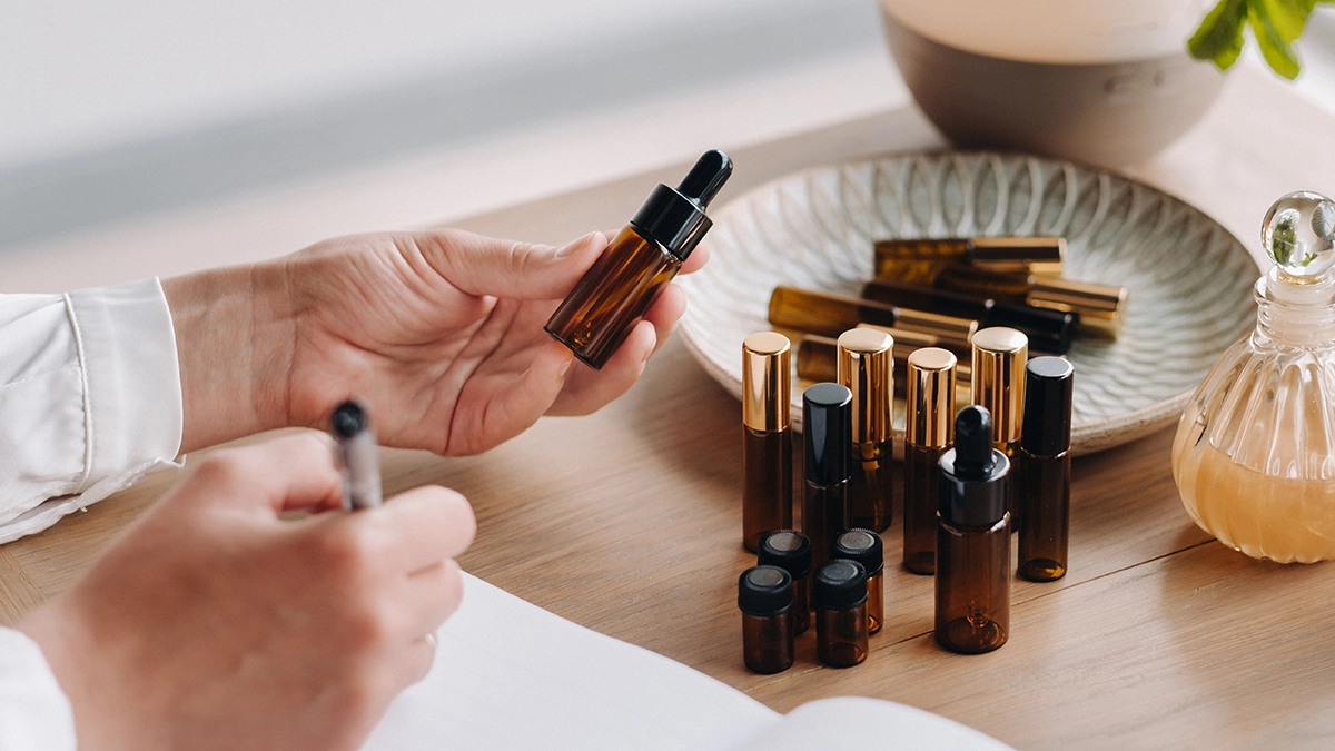 A person holding an essential oil bottle, surrounded by various oils and a diffuser, representing the process of using essential oils for vertigo relief