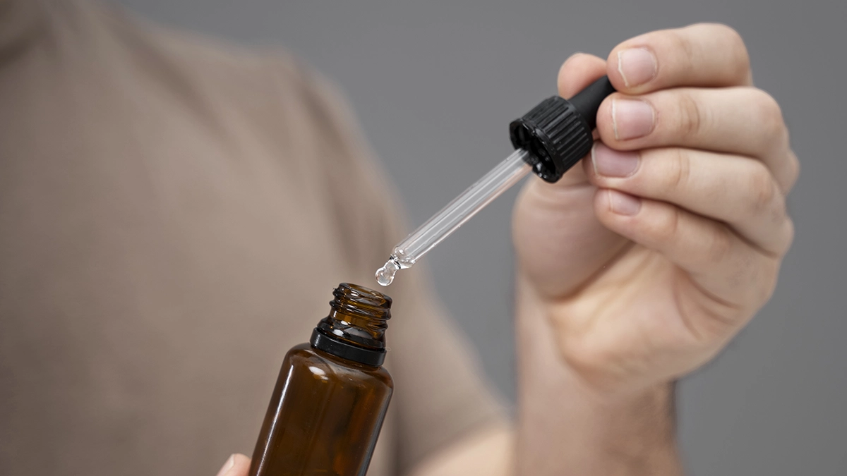 A person holds a dropper and essential oil bottle, illustrating how to use essential oils for treating minor burns