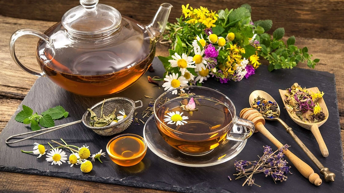 A teapot and cup filled with herbal tea, surrounded by various herbs and flowers, suggesting natural remedies for vertigo