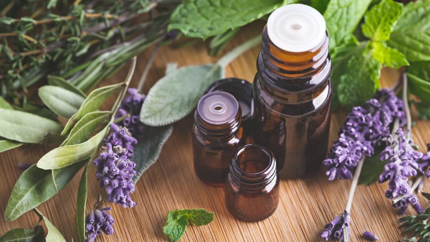 Amber bottles of essential oils with herbs like lavender and mint, known to soothe itchy skin by calming irritation and reducing inflammation