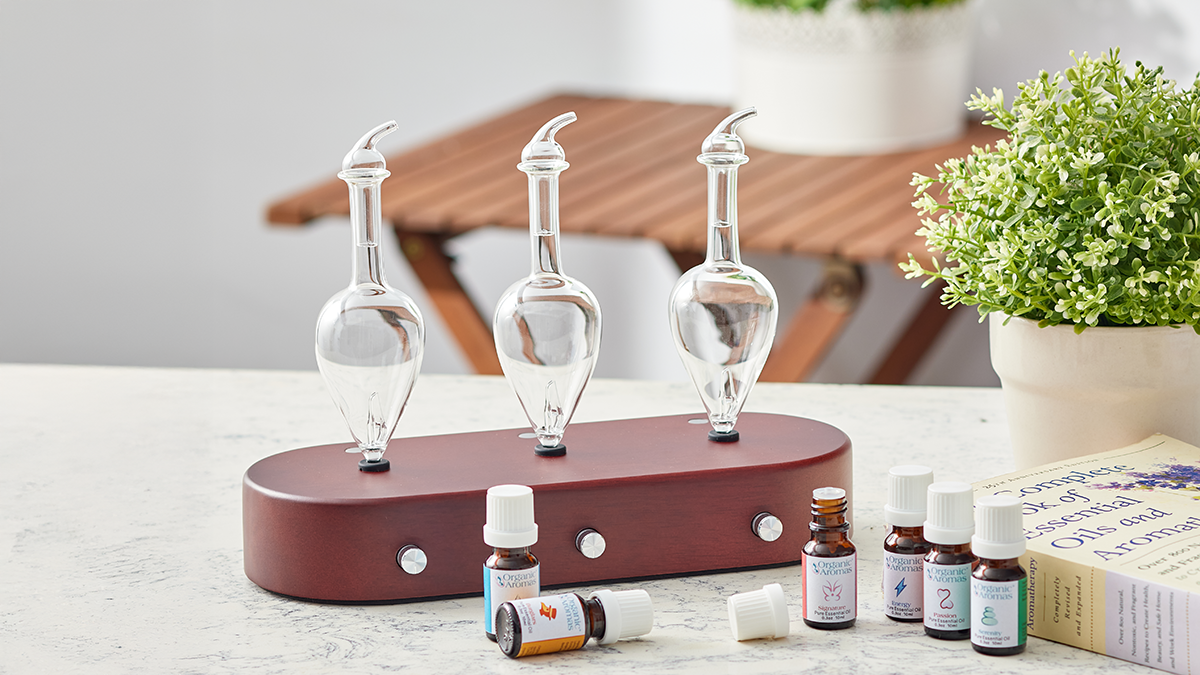 Atta Nebulizing diffusers on a wooden base with essential oils, a book, and a plant, ideal for spreading pure aromas in large spaces