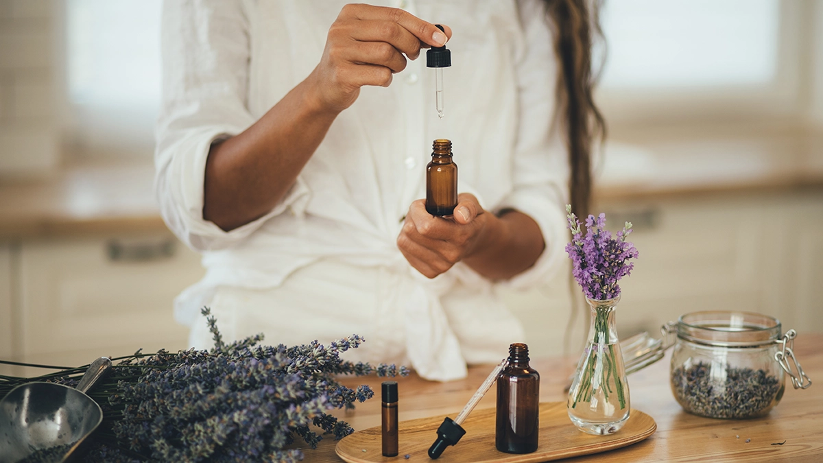 Person holding a dropper with essential oil beside fresh lavender, highlighting natural remedies for treating earaches