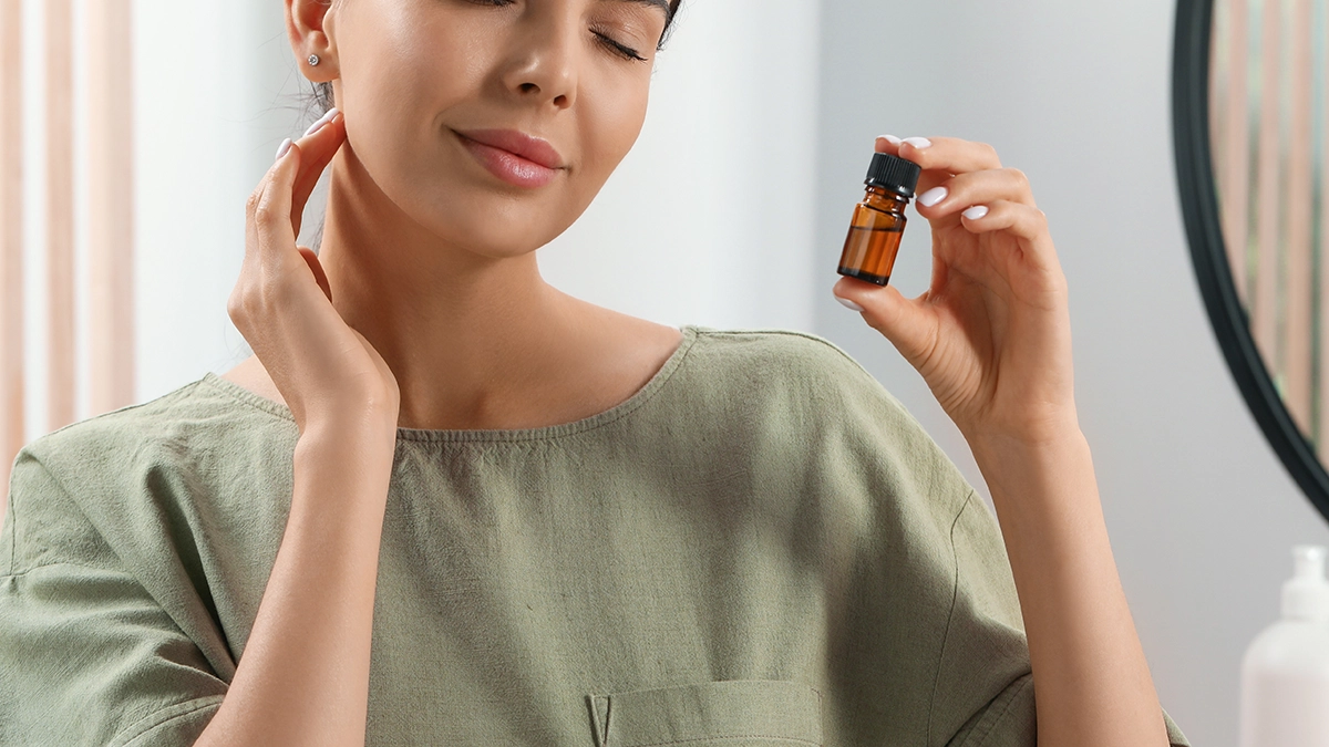 Woman enjoying the scent of an essential oil bottle, suggesting its calming benefits for managing OCD symptoms