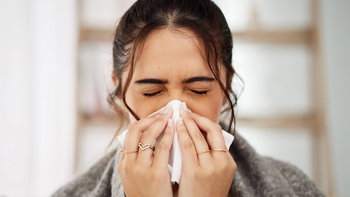 Woman sneezing into a tissue, showing nasal congestion