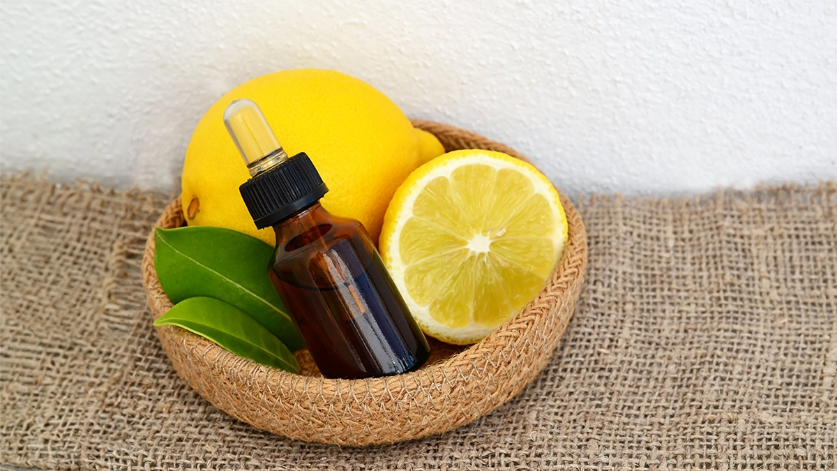 bottle of essential oil sits in a woven bowl with lemons and green leaves, symbolizing essential oils for detoxification