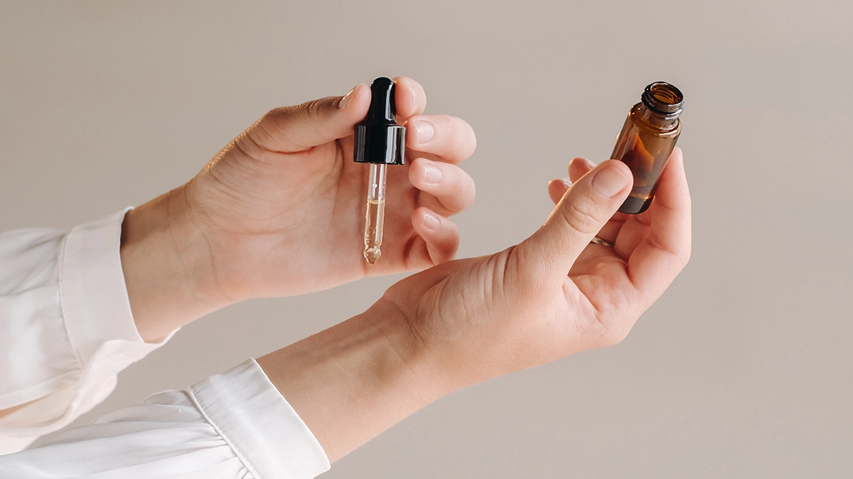 Hands holding an essential oil dropper, suggesting relief for Carpal Tunnel Syndrome