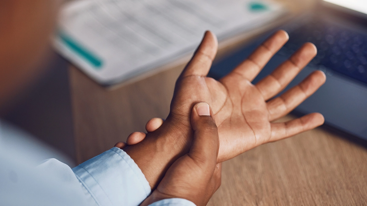 Person holding their wrist, indicating possible discomfort from Carpal Tunnel Syndrome