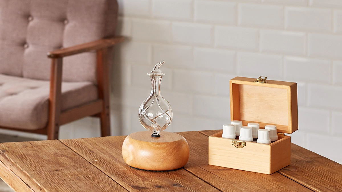 Nebulizing diffuser and Organic Aromas essential oils displayed on a wooden table in a cozy, minimalist room.