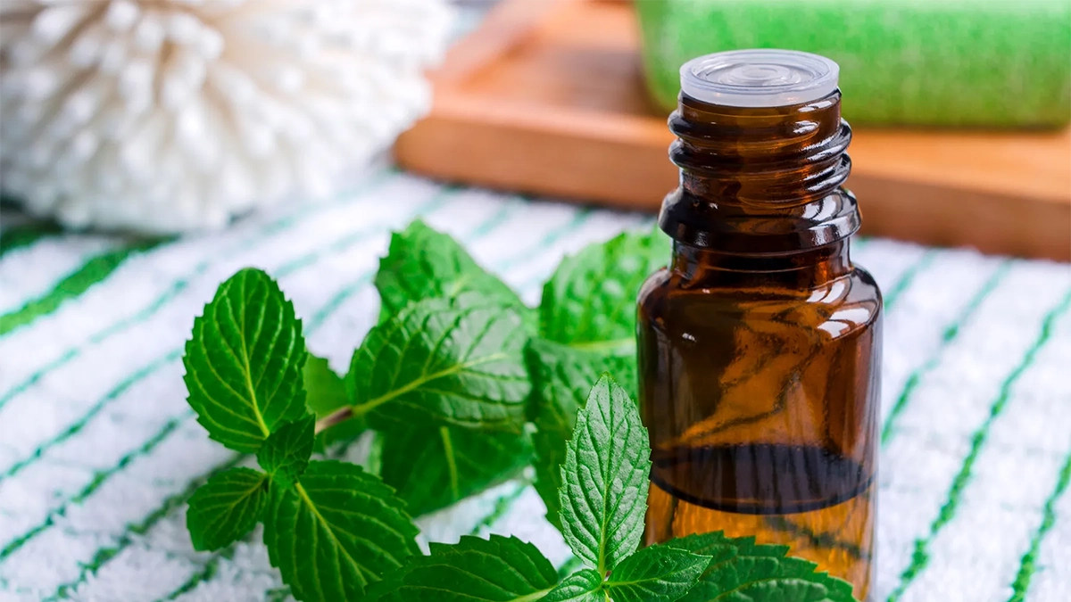 Amber essential oil bottle with fresh peppermint leaves on a textured cloth