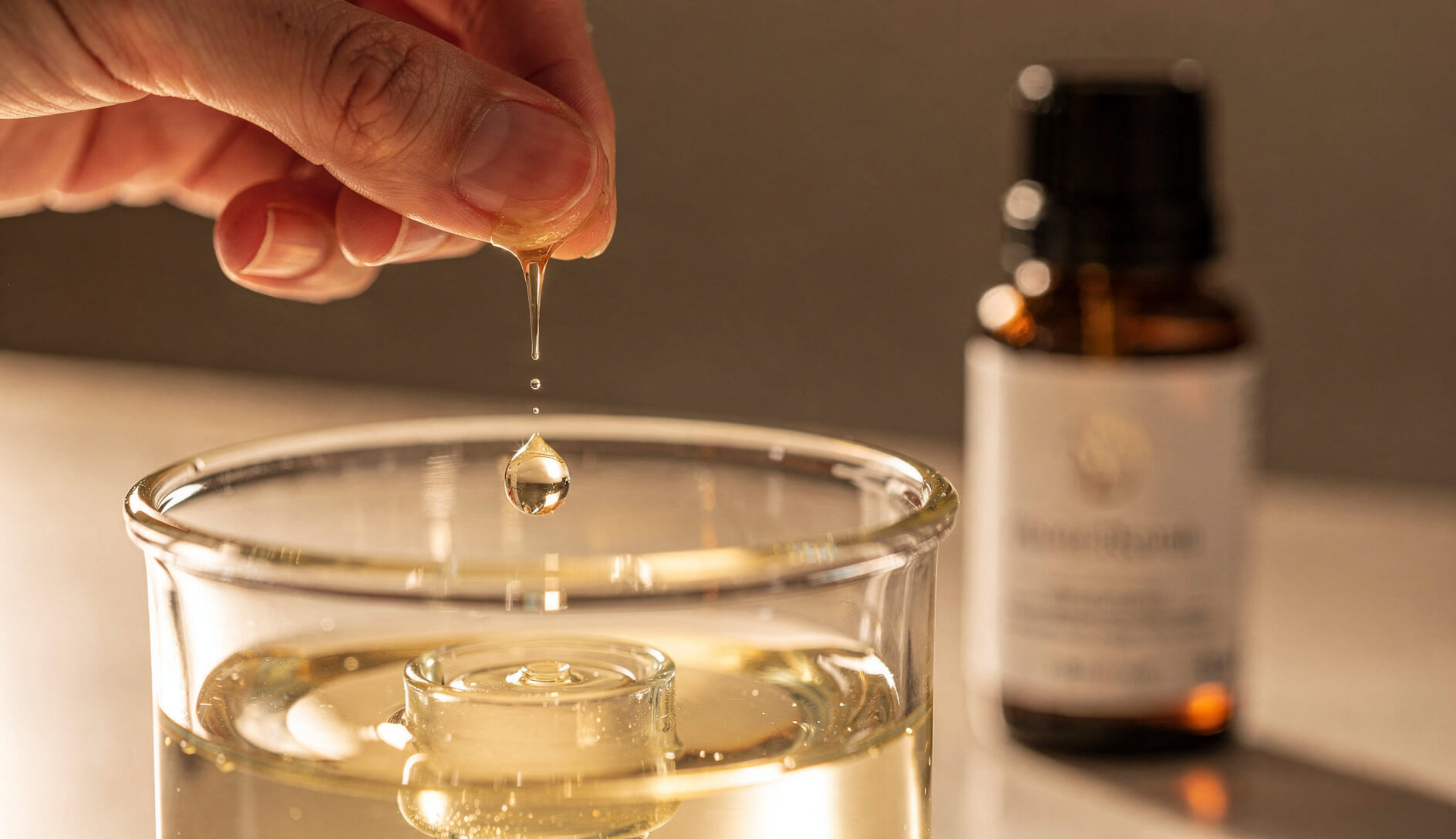 Close-up of essential oil drops being added to glass nebulizing diffuser reservoir