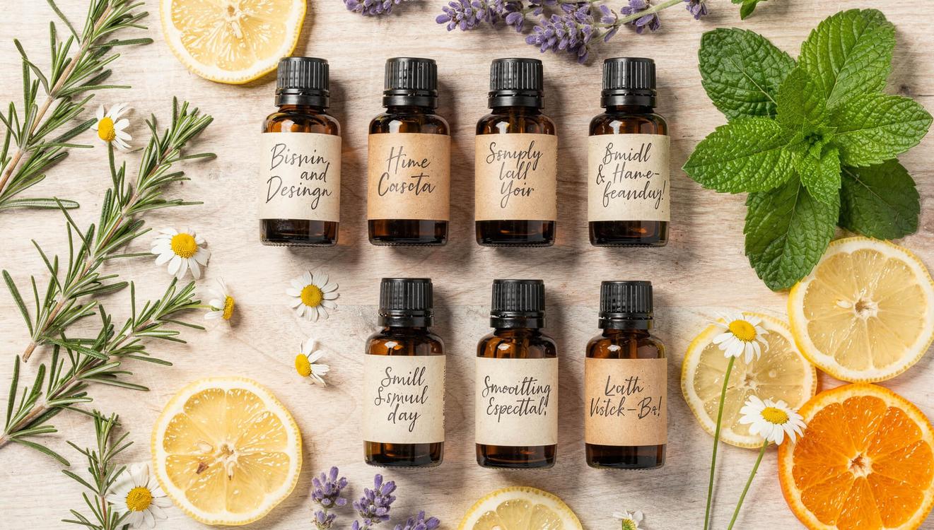 Essential oil bottles with rosemary chamomile lavender and peppermint on wood surface