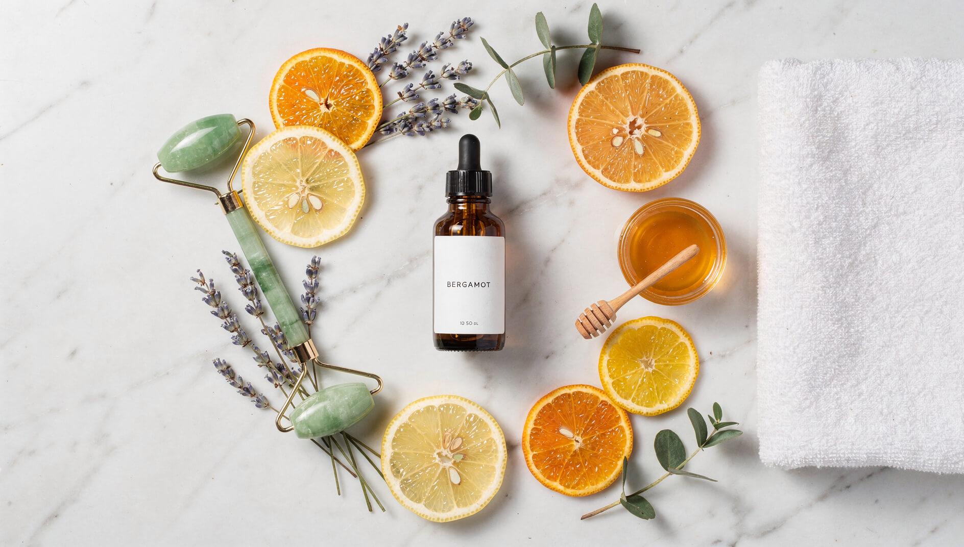 Wellness flat lay with bergamot essential oil, citrus slices, and self-care items