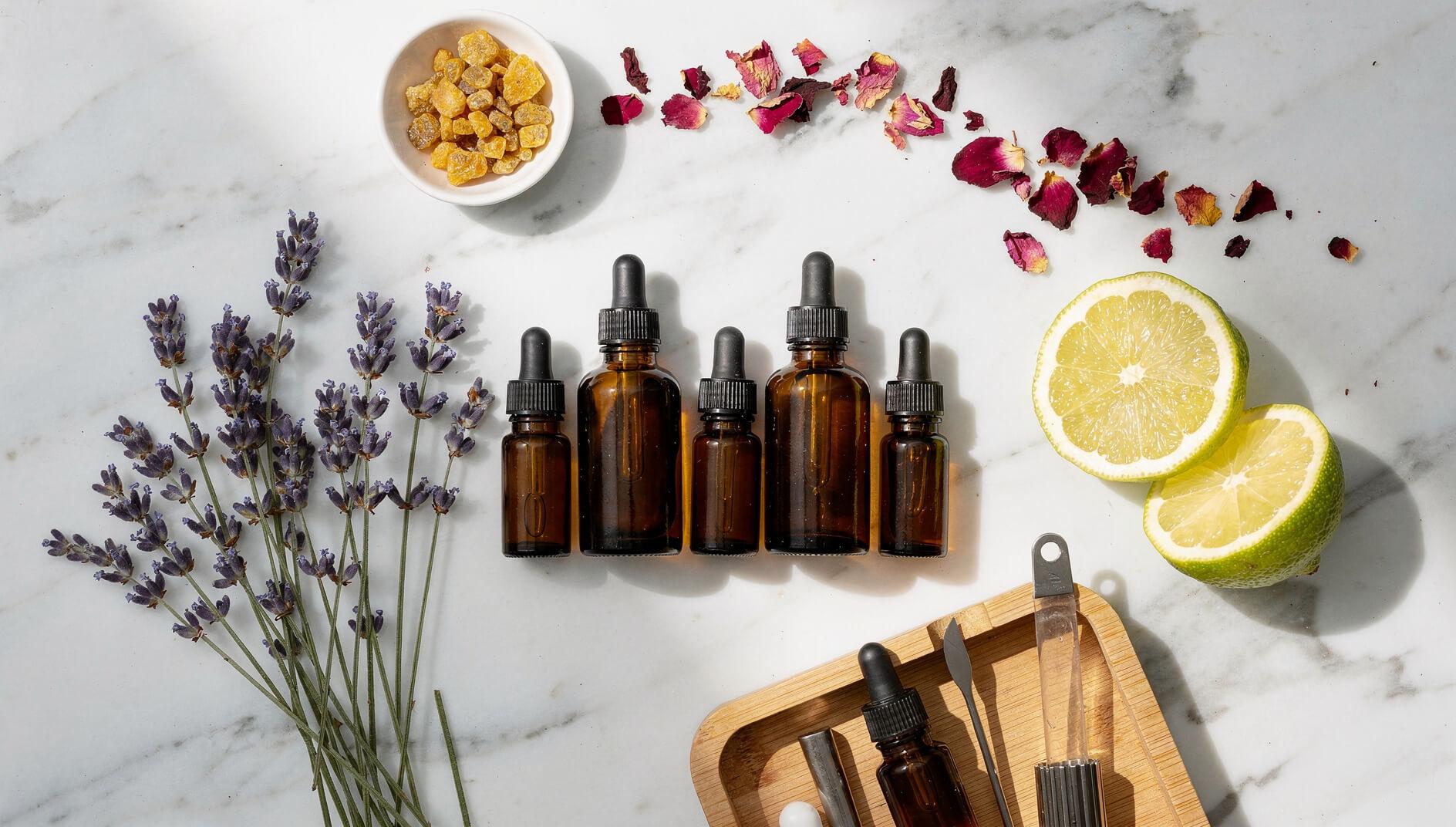 Essential oil blending setup with frankincense resin, lavender, bergamot, and amber bottles